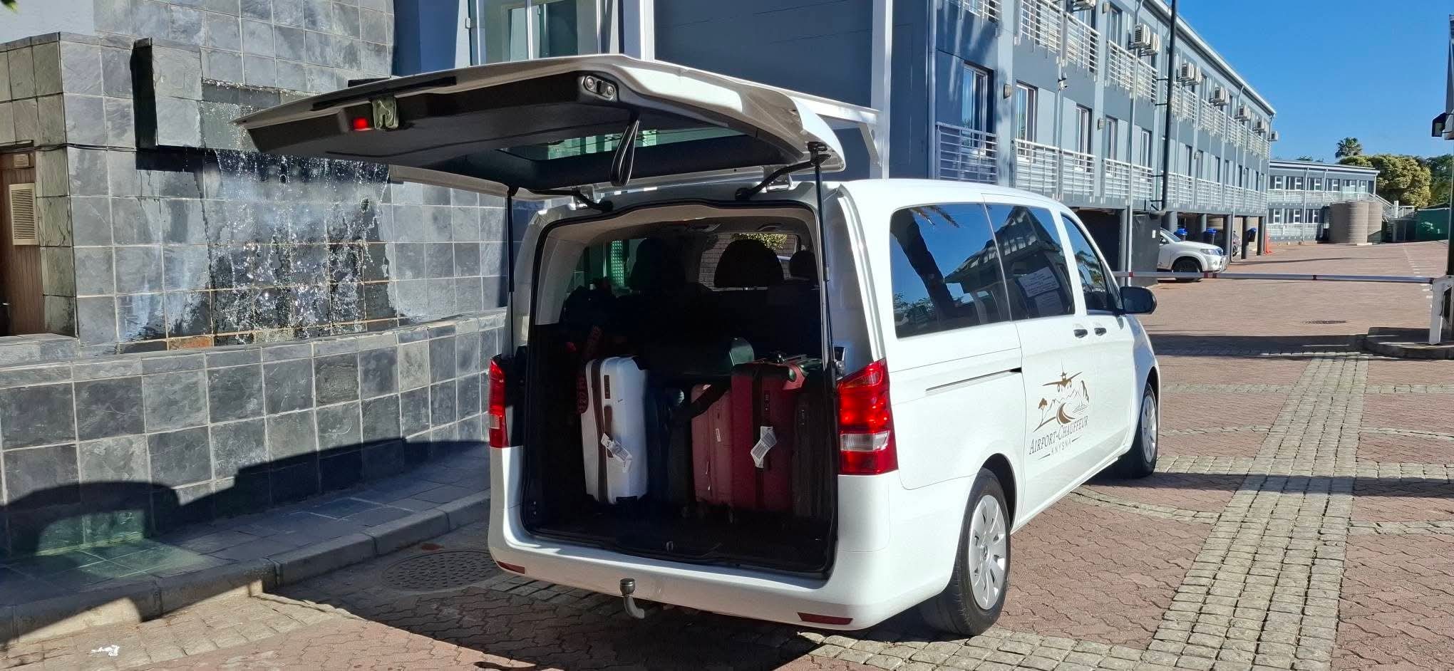 Chauffeur van with rear door open loaded with suitcases at a hotel